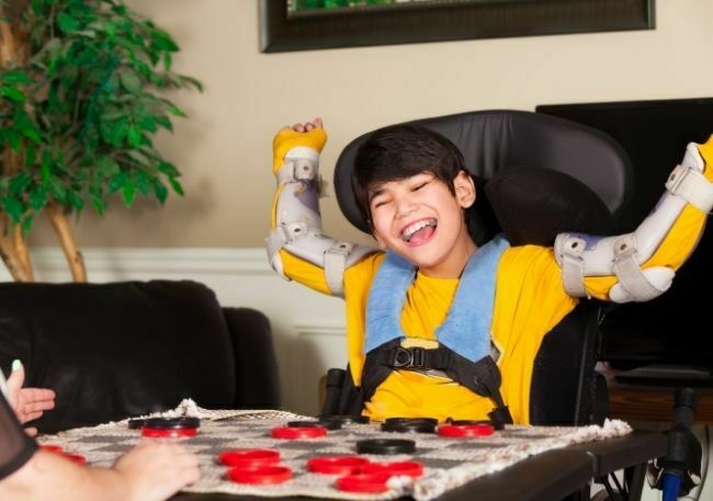 Terapia zajęciowa- chłopiec z niepełnosprawnością ruchową może grać w gry.